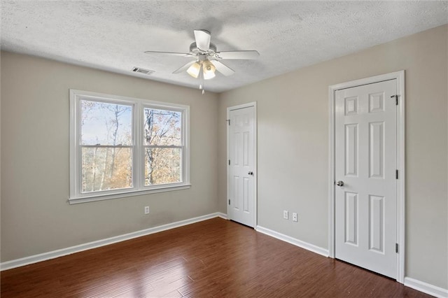 unfurnished bedroom with ceiling fan, dark hardwood / wood-style floors, and a textured ceiling