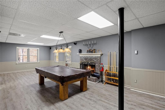 recreation room featuring a fireplace, hardwood / wood-style floors, a drop ceiling, and pool table