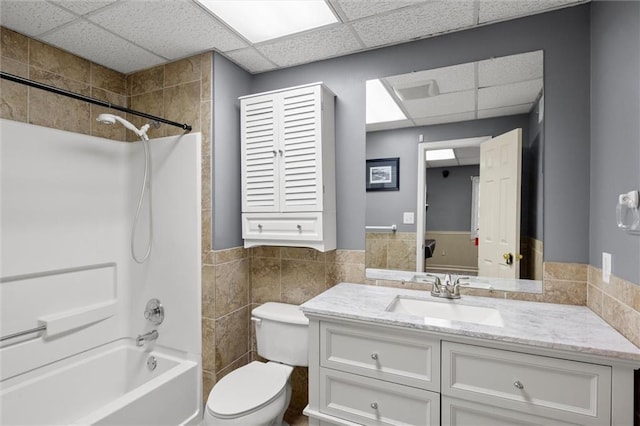 full bathroom with a paneled ceiling, toilet, vanity, and washtub / shower combination