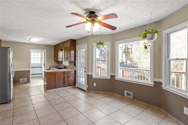 kitchen featuring stainless steel fridge, light tile patterned floors, ceiling fan, and sink