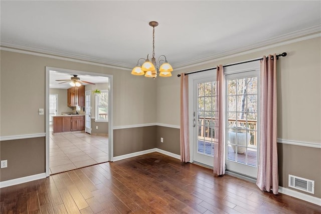 unfurnished dining area with ceiling fan with notable chandelier, crown molding, and light hardwood / wood-style flooring