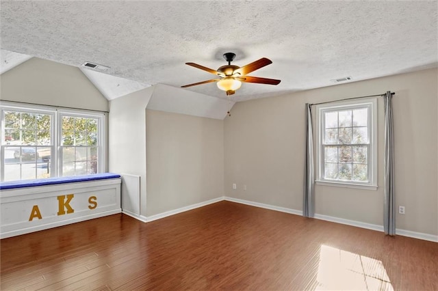 spare room featuring a textured ceiling, dark hardwood / wood-style flooring, vaulted ceiling, and ceiling fan