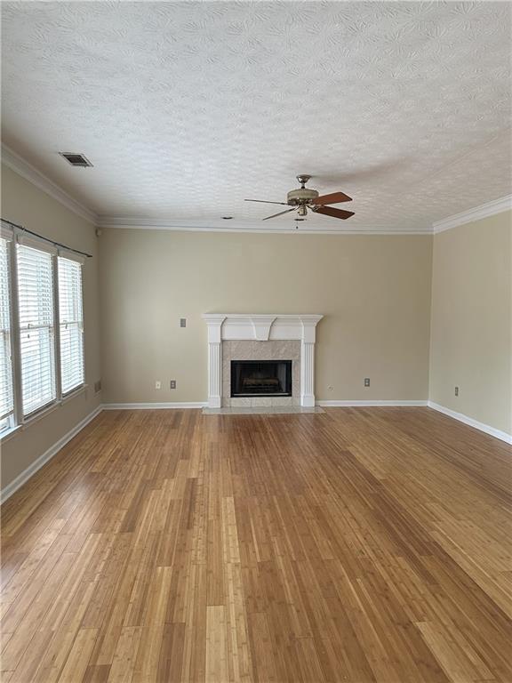 empty room with crown molding, hardwood / wood-style floors, a textured ceiling, and an inviting chandelier