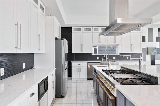 kitchen with tasteful backsplash, appliances with stainless steel finishes, wall chimney range hood, and a sink