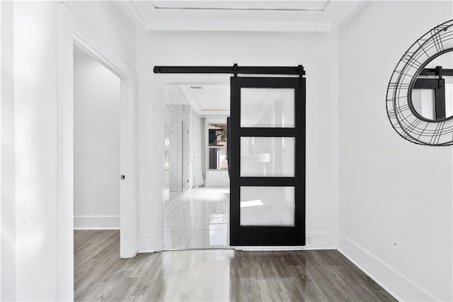 entrance foyer featuring a barn door, wood finished floors, and baseboards