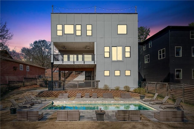 back of property with fence, board and batten siding, a fenced in pool, a balcony, and a patio area