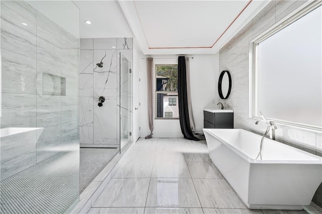 bathroom featuring a marble finish shower, a freestanding bath, and vanity