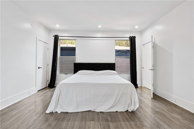 bedroom featuring recessed lighting, multiple windows, baseboards, and wood finished floors