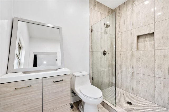 bathroom featuring vanity, toilet, and a tile shower