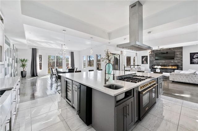 kitchen with double oven range, island exhaust hood, a sink, open floor plan, and a large fireplace