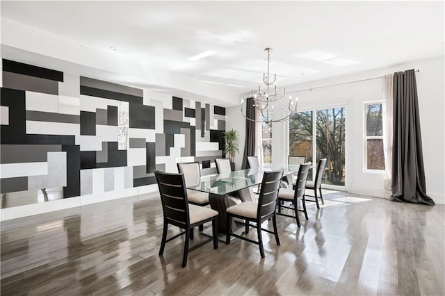 dining area featuring wallpapered walls, an accent wall, baseboards, an inviting chandelier, and wood finished floors