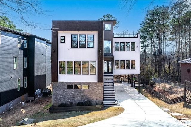 view of front facade with stairs, central AC, and stucco siding