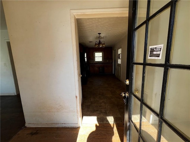 corridor with a notable chandelier and a textured ceiling