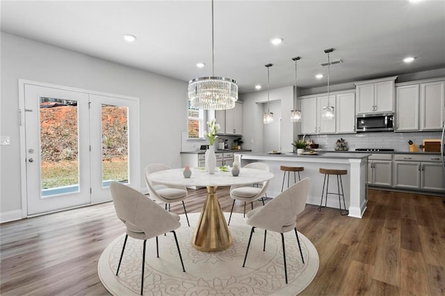 dining space with visible vents, recessed lighting, dark wood-type flooring, and an inviting chandelier