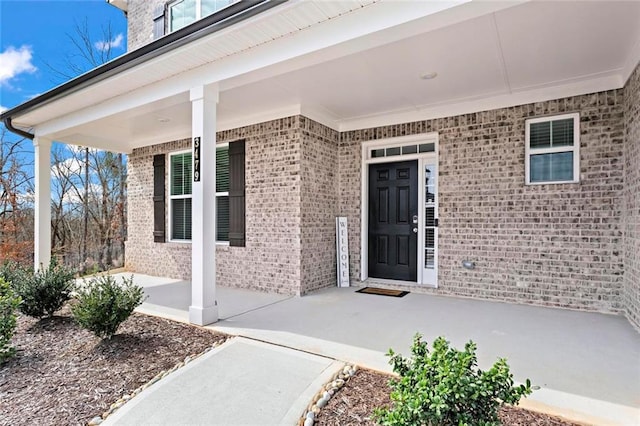 entrance to property featuring brick siding and a patio area