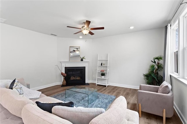 living room featuring visible vents, baseboards, wood finished floors, and a ceiling fan