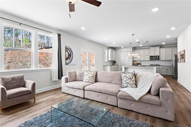 living room with a ceiling fan, recessed lighting, wood finished floors, and baseboards