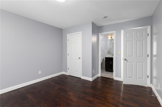 unfurnished bedroom featuring dark wood-type flooring and connected bathroom