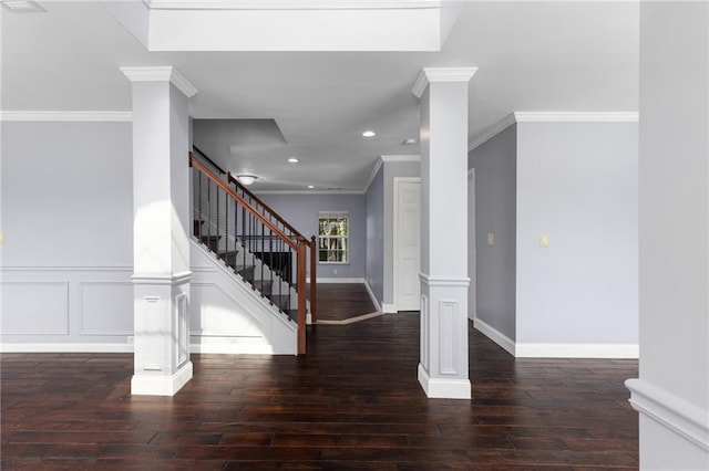 foyer entrance featuring dark wood-type flooring, ornamental molding, and ornate columns