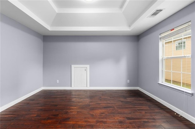 spare room with dark hardwood / wood-style flooring and a tray ceiling