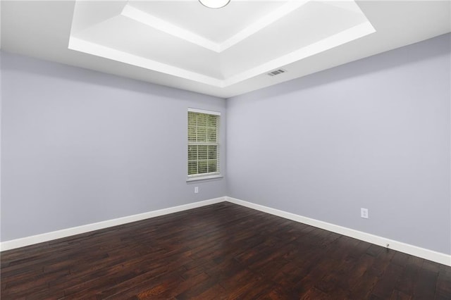 spare room featuring wood-type flooring and a tray ceiling