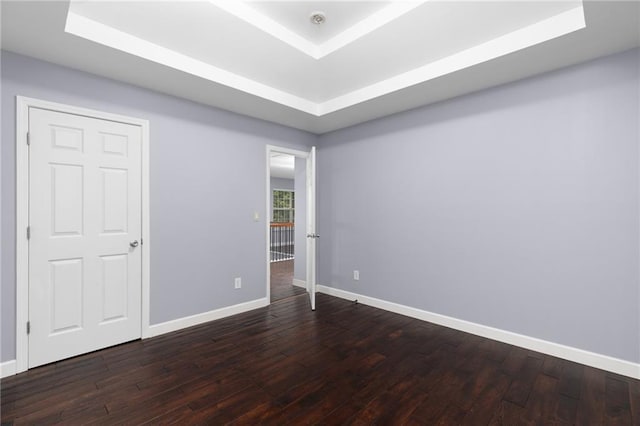 spare room with dark hardwood / wood-style floors and a tray ceiling