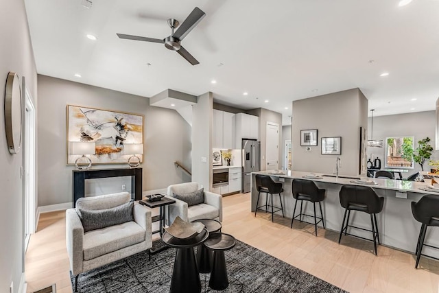 living room featuring sink, ceiling fan, and light hardwood / wood-style floors