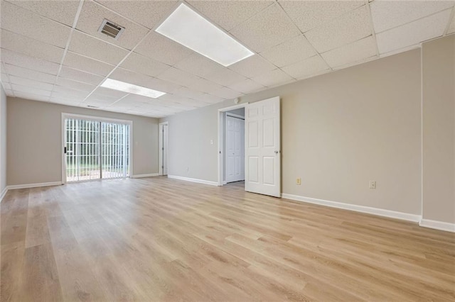 unfurnished room with light wood-type flooring and a drop ceiling