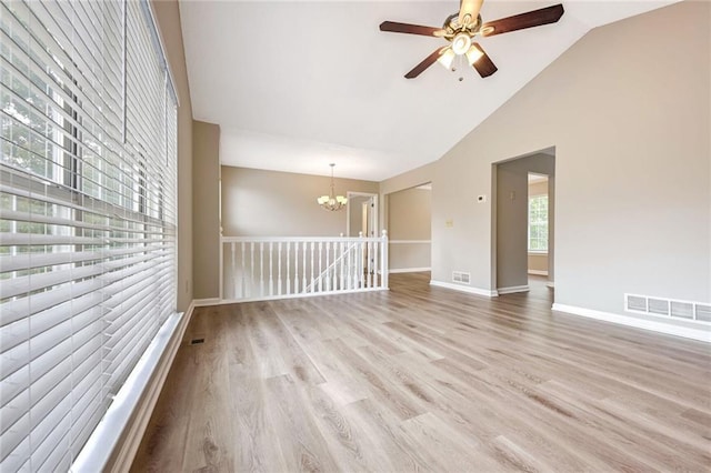 unfurnished room featuring light hardwood / wood-style floors, ceiling fan with notable chandelier, and high vaulted ceiling