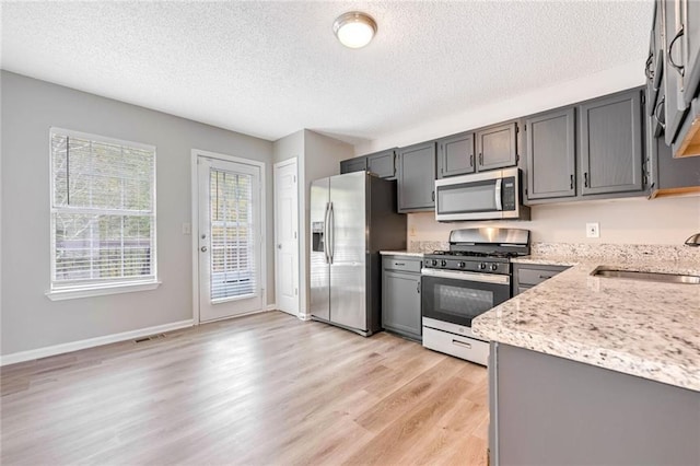 kitchen featuring gray cabinetry, appliances with stainless steel finishes, sink, and light hardwood / wood-style flooring