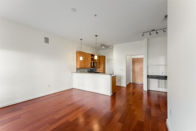 870 Inman Village Pkwy Unit 203, Atlanta, GA 30307 - kitchen with a peninsula, rail lighting, dark wood-style flooring, stainless steel microwave, and brown cabinets