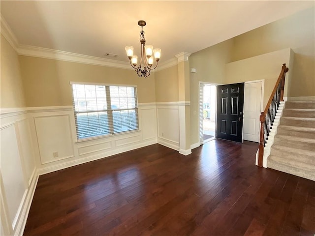 foyer entrance with a notable chandelier, visible vents, dark wood-type flooring, ornamental molding, and stairs