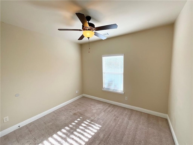 spare room featuring light carpet, visible vents, a ceiling fan, and baseboards