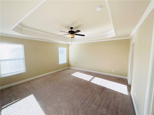 empty room with carpet, baseboards, a raised ceiling, and ornamental molding