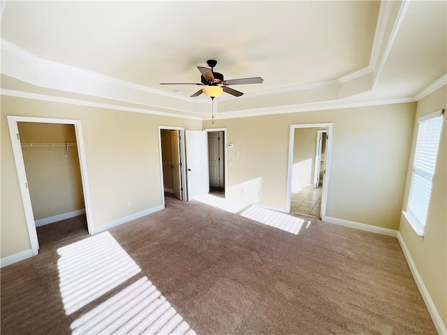 unfurnished bedroom with baseboards, ornamental molding, a raised ceiling, and light colored carpet