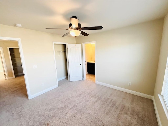 unfurnished bedroom with light carpet, baseboards, a ceiling fan, ensuite bath, and a closet