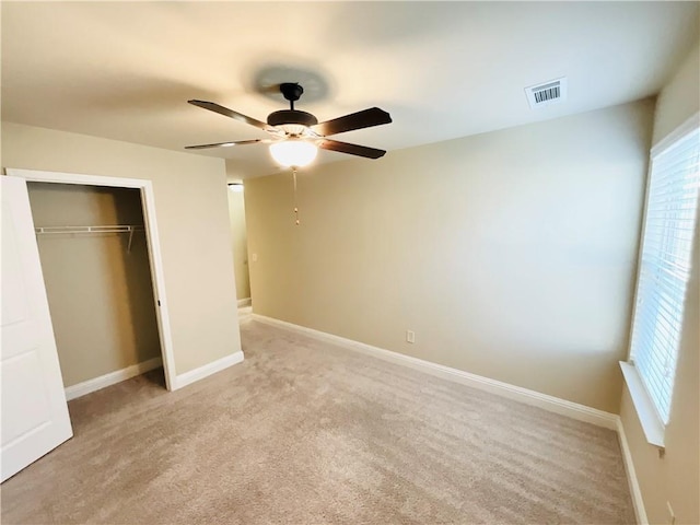 unfurnished bedroom with a closet, visible vents, light carpet, and baseboards