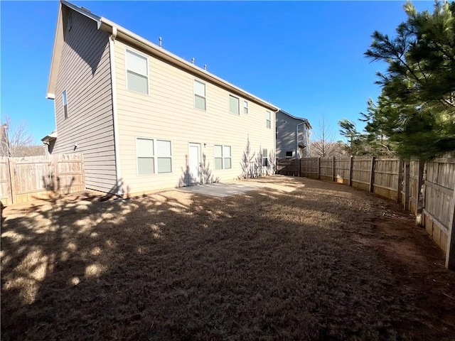 rear view of property featuring a fenced backyard and a patio