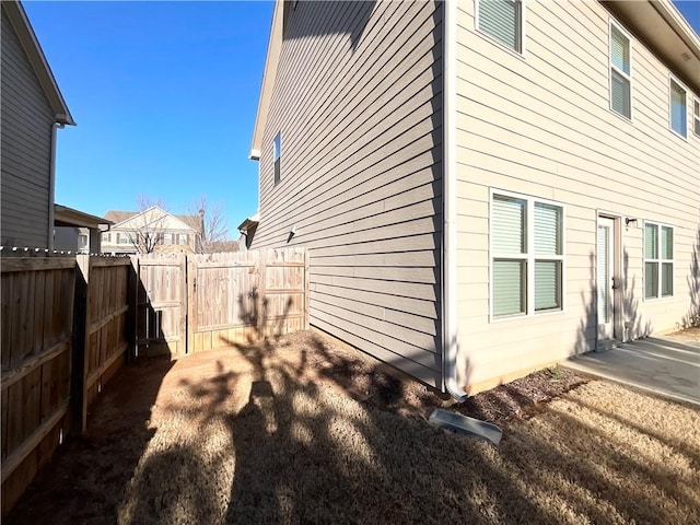 view of side of home featuring a patio and a fenced backyard