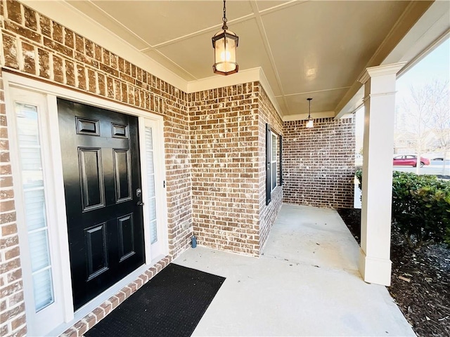 doorway to property with a porch and brick siding