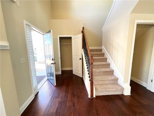 entryway featuring a towering ceiling, stairway, baseboards, and hardwood / wood-style floors