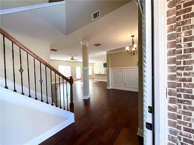 entrance foyer featuring ceiling fan with notable chandelier, a wainscoted wall, visible vents, stairway, and decorative columns