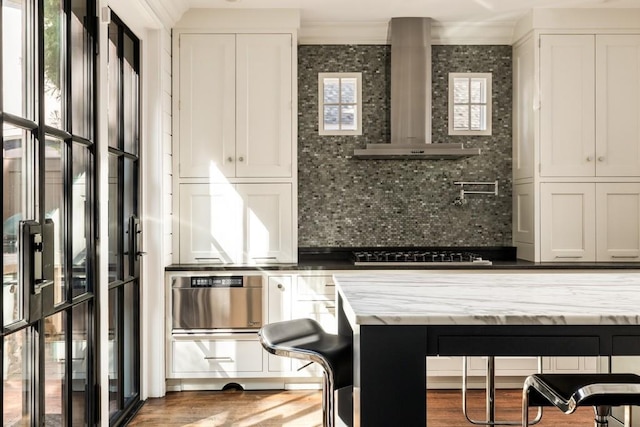 31 Lafayette Dr NE, Atlanta, GA 30309 - kitchen with wall chimney exhaust hood, decorative backsplash, white cabinets, gas stovetop, and light stone countertops