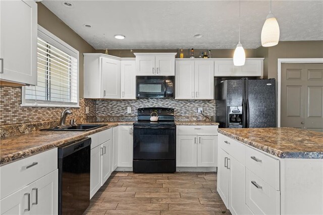 kitchen featuring black appliances, sink, hanging light fixtures, light hardwood / wood-style flooring, and white cabinetry