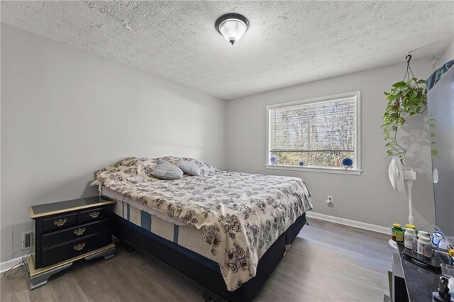 bedroom featuring a textured ceiling and dark hardwood / wood-style floors