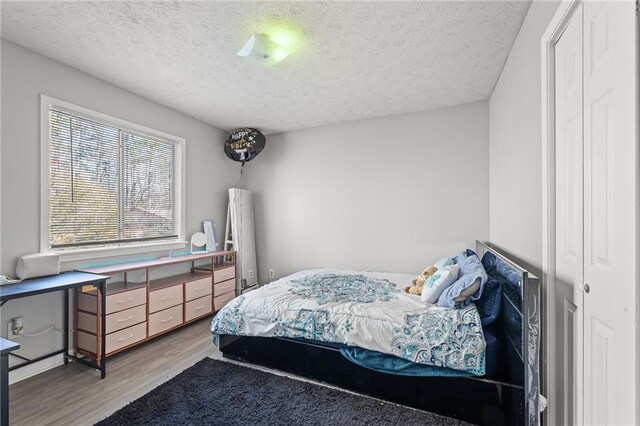 bedroom featuring wood-type flooring, a textured ceiling, and a closet