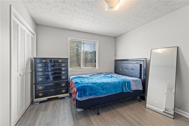 bedroom with a closet, wood-type flooring, and a textured ceiling