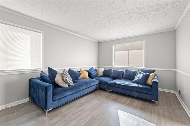 living room featuring hardwood / wood-style floors, a textured ceiling, and ornamental molding