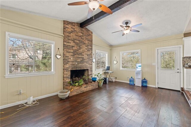 unfurnished living room featuring a fireplace, dark hardwood / wood-style flooring, lofted ceiling with beams, and ceiling fan