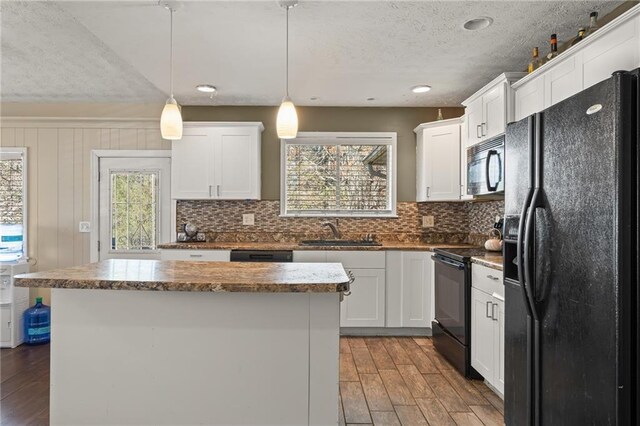 kitchen with a center island, sink, decorative light fixtures, white cabinets, and black appliances